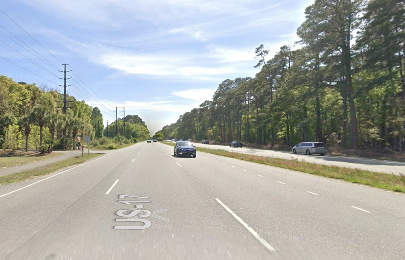 US Highway 17 at Murrells Inlet from the roadway. The paved walking path runs along the left edge, separated from the traffic lanes by a narrow strip of grass.